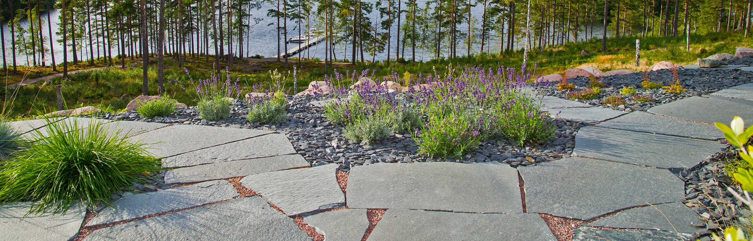 Uteplats med oregelbunden skiffer Offerdal och utsikt över en sjö.