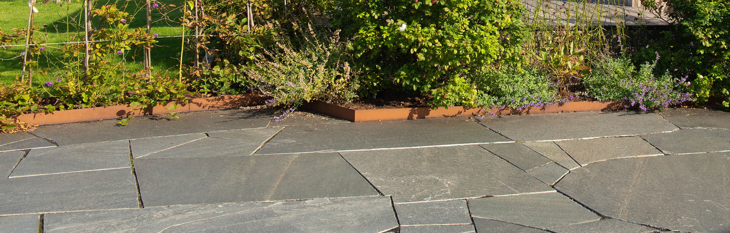 Grå oregelbunden skiffer Offerdal och kantstål i corten mot rabatt