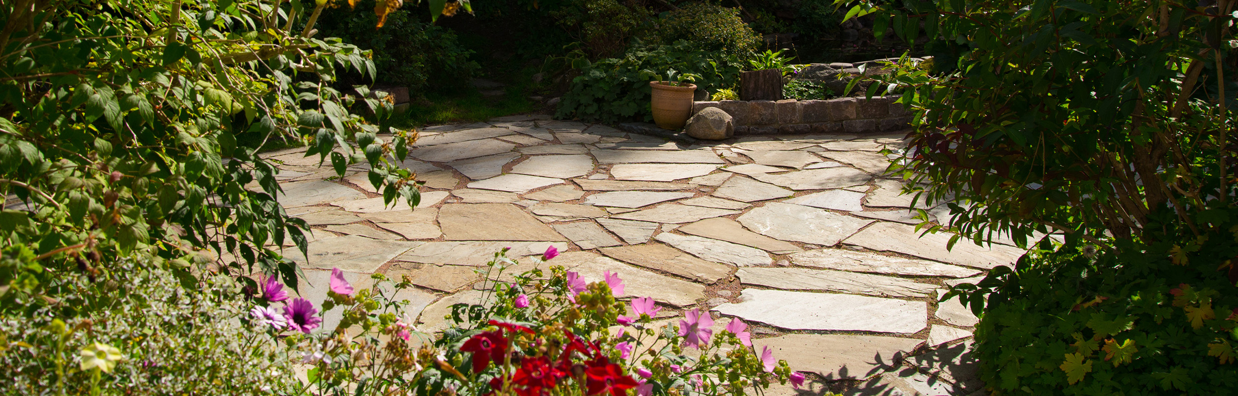 Uteplats i oregelbunden sandfärgat skiffer.