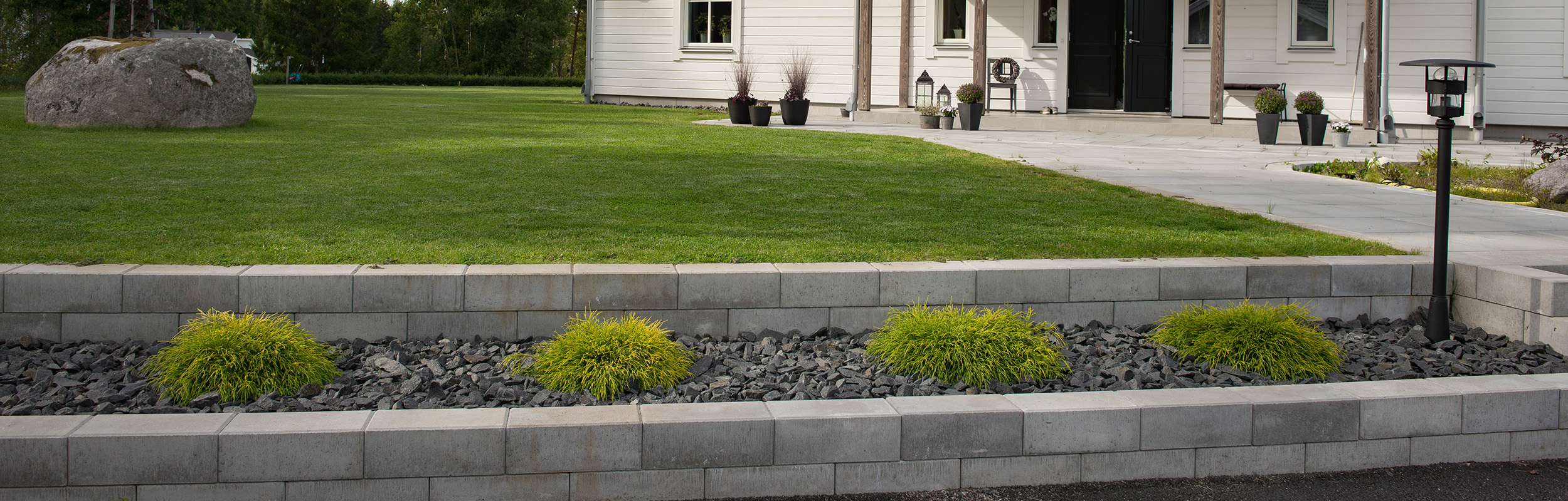 Mur med Basic mursten och stenrabatt med diabaskross i grafit