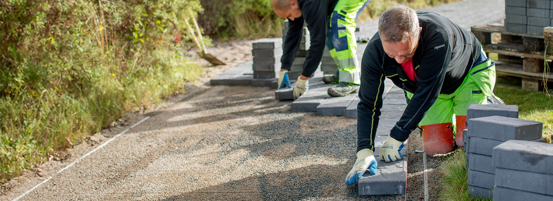 Två stenläggare som lägger marksten